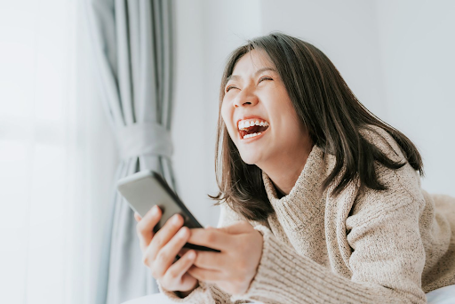 A woman laughing while holding a phone