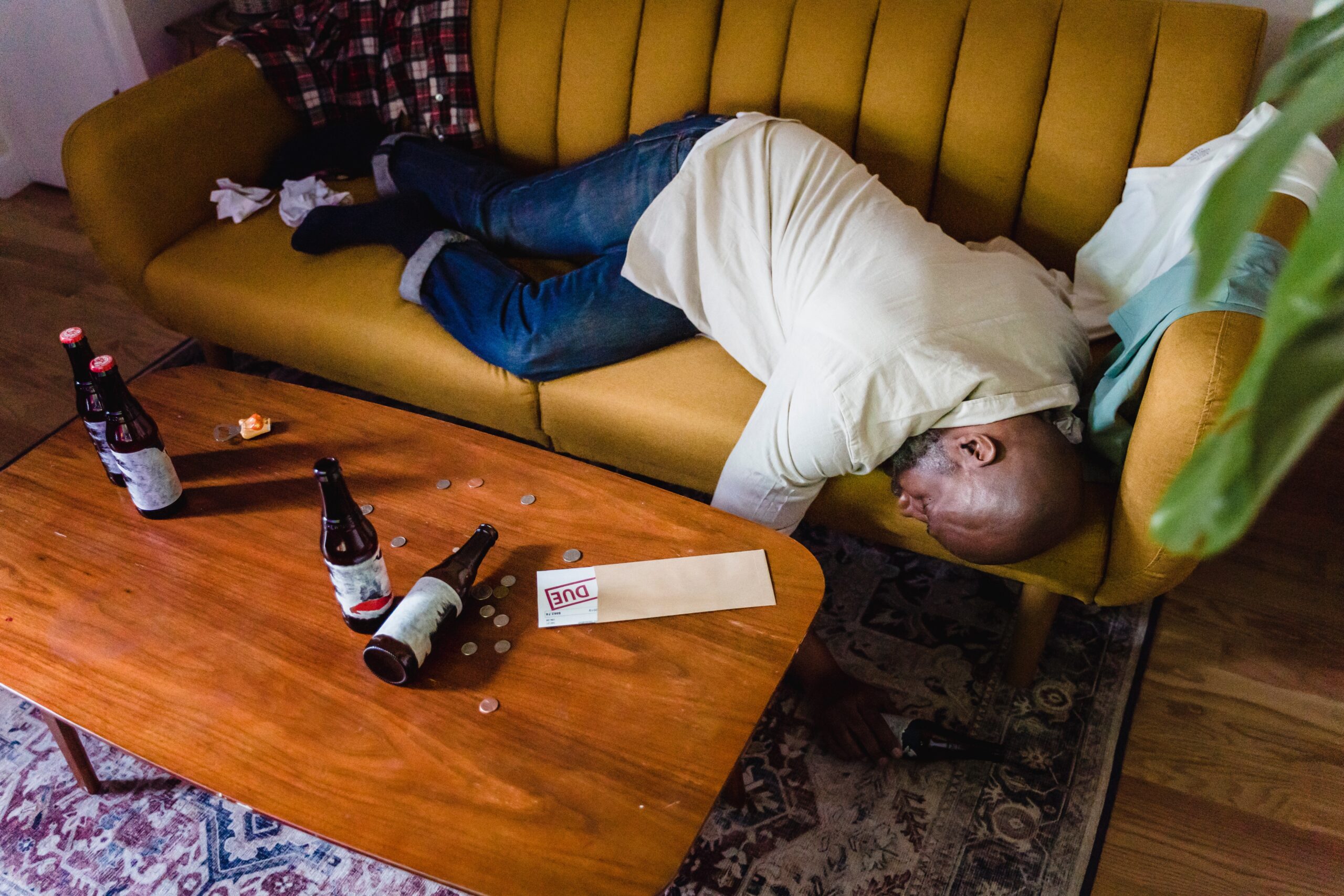 A man lying on the couch with alcohol bottles
