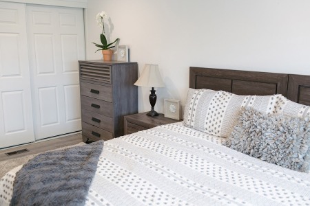 A well-furnished bedroom that features a bed, dresser, and nightstand.