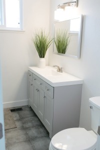 A bathroom with a white wall, toilet, sink, and mirror.