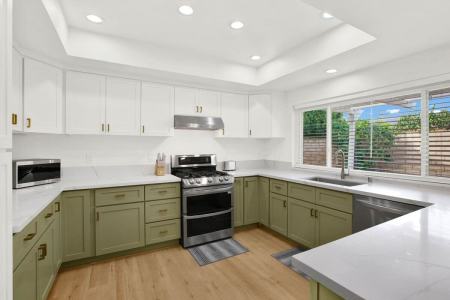 A modern kitchen featuring white and green cabinets and white countertops.