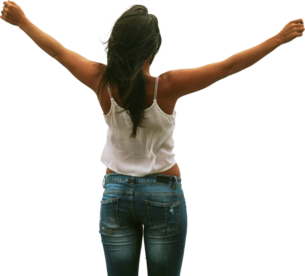 A woman in jeans and a white tank top joyfully raises her arms, expressing a sense of freedom and happiness.