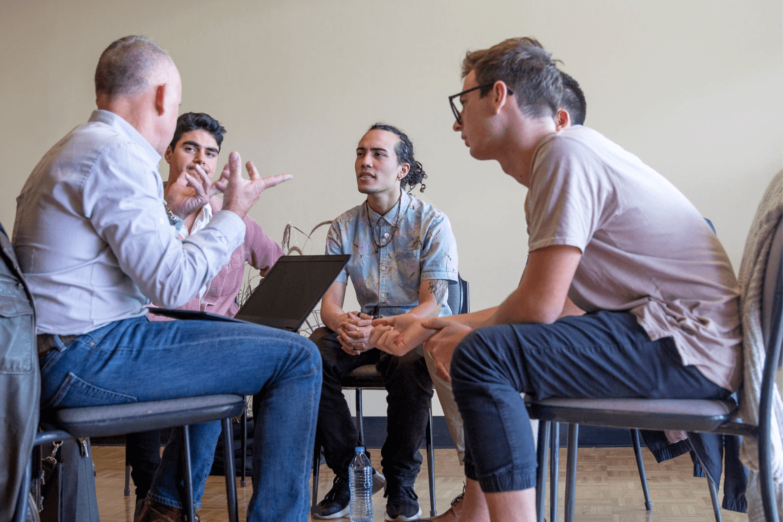 A group of individuals engaged in a focused discussion around a table, with an addiction specialist suggesting active participation and exchanging ideas.