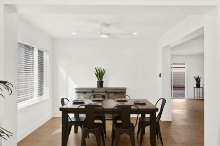 A white-walled dining room with wooden floors furnished with a sleek dining set.