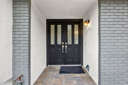 A black door in the entryway of a home with white and grey brick walls.