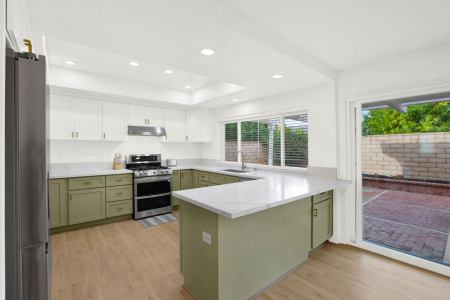 A kitchen with green cabinets and white appliances.