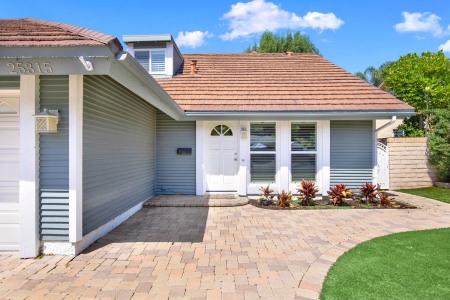 A suburban home with a driveway leading up to the house, surrounded by lush green grass.