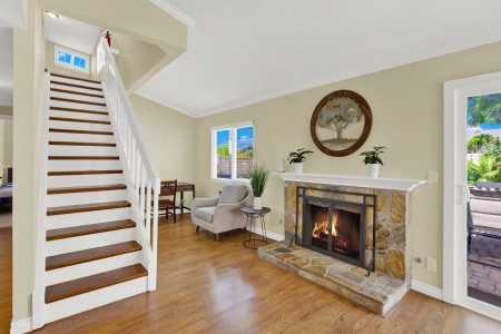A cozy living room with a fireplace and stairs creates a warm and inviting atmosphere.