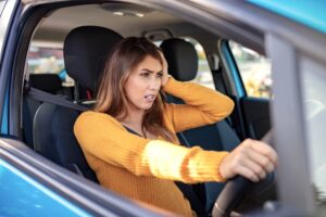 Anxious woman in a yellow shirt looks frustrated while driving