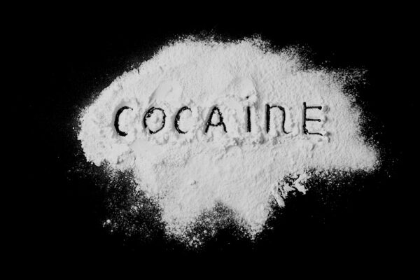 White powder on a black surface with the word cocaine etched