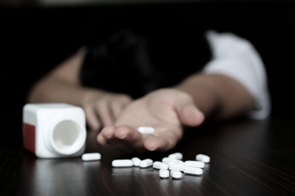 Anxious man reaching for white Xanax pills spilled from a white bottle