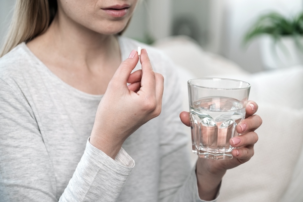 Woman taking an alprazolam pill with a glass of water