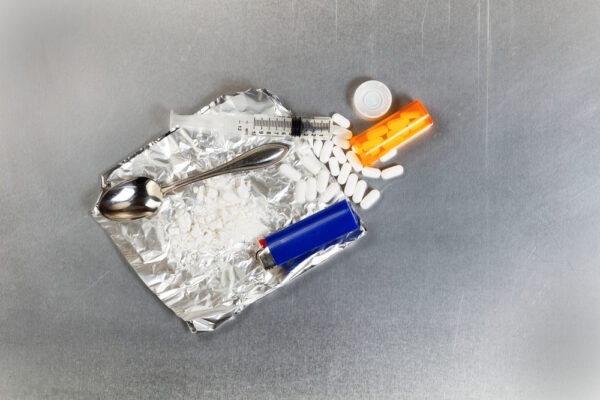 Drug paraphernalia with a lighter, white pills, aluminum foil and spoon