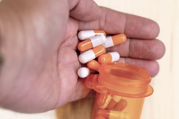 Adderall capsules from a pill bottle being poured into a palm of a hand