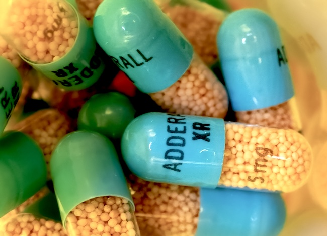 Close-up of blue and orange Adderall capsules in a pill bottle