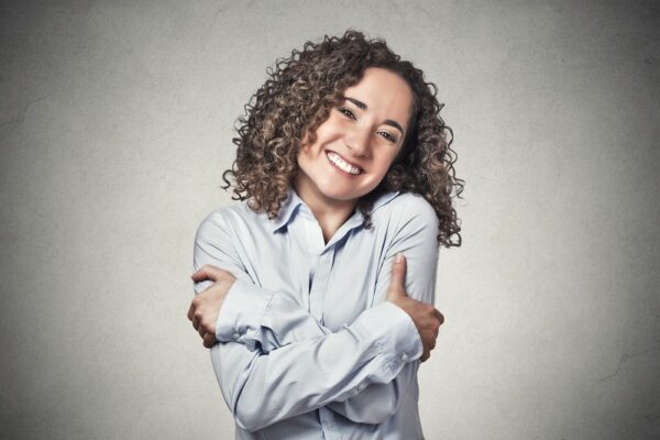 Woman with curly hair hugging herself