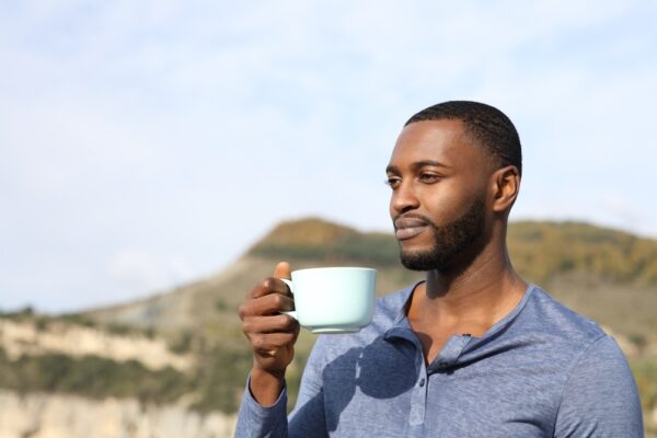 Man drinking tea reflecting outdoors