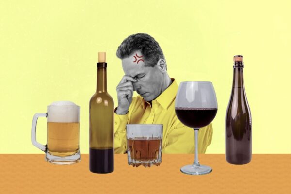 Man holding his head with different types of alcohol in front of him