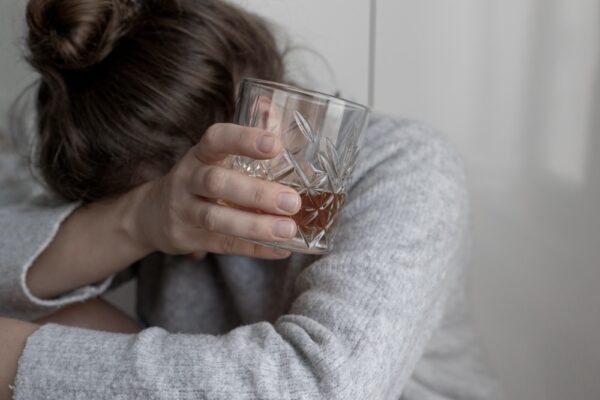 A woman crying while drinking whisky.