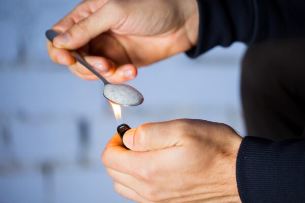 Man heating crack cocaine with a lighter and spoon