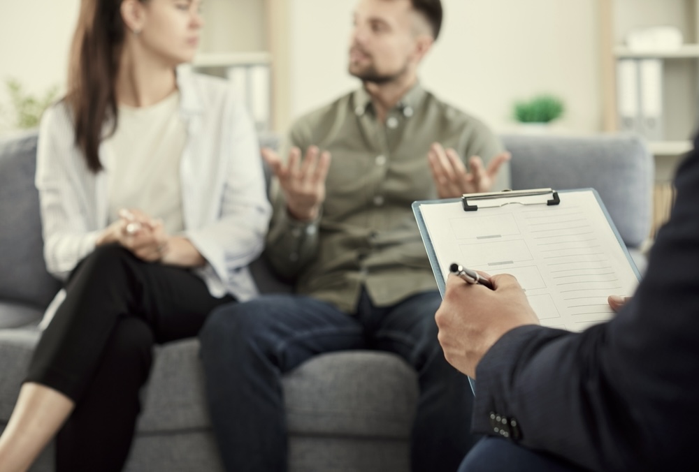 Husband and wife looking upset while speaking to a family therapist