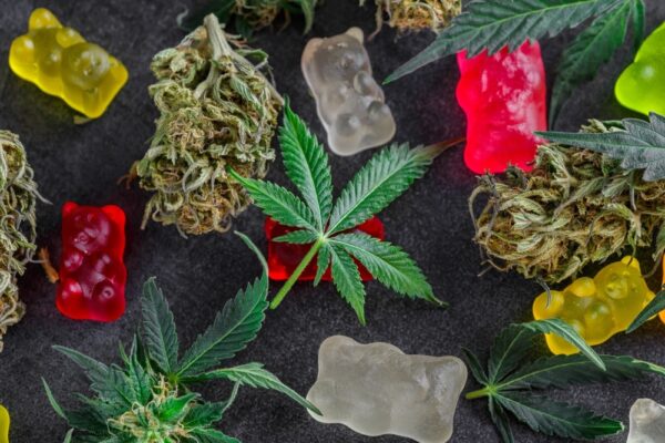 MArijuana gummies edibles and leaves on a dark surface