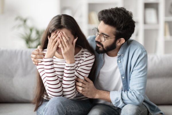 Husband supporting his wife in rehab while sitting on a couch