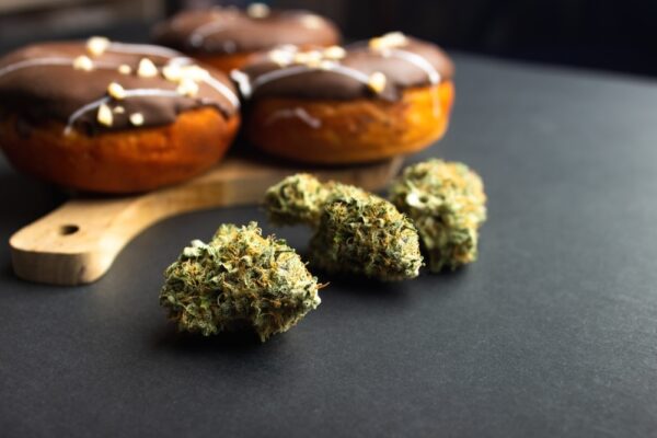 Dry buds of cannabis with marijuana infused edible donuts in the background