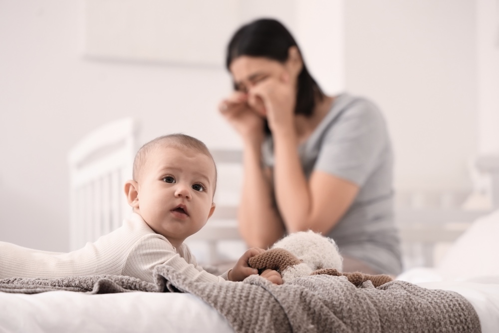 New mother crying on the bed with a baby in front of her