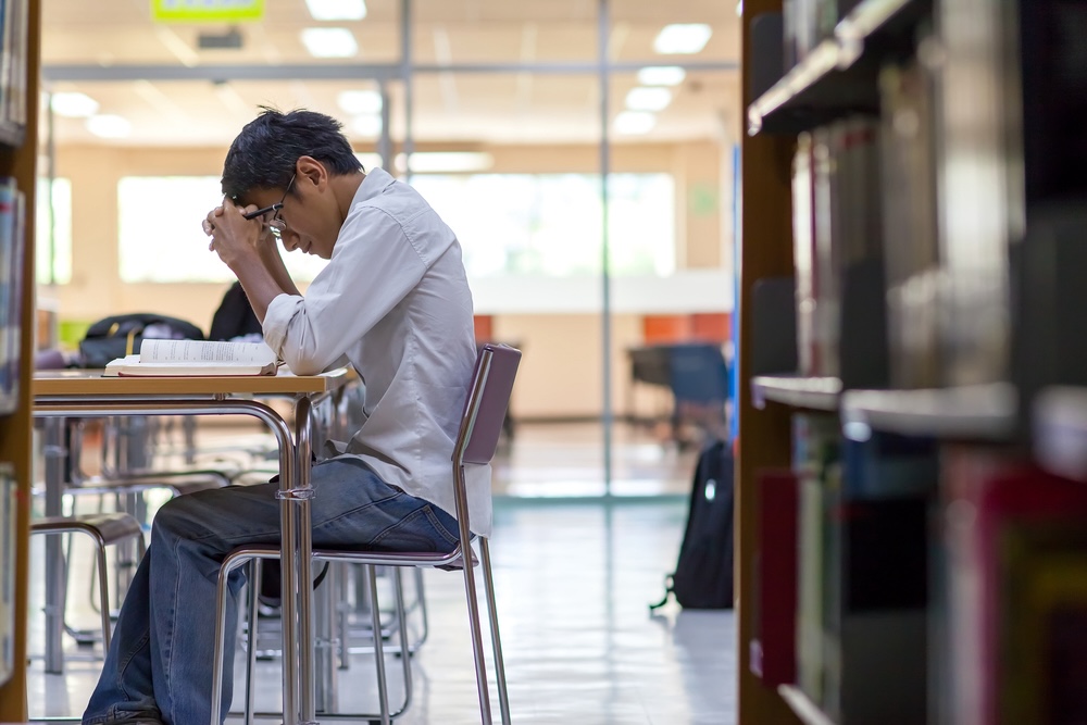 Man in a library studying considering taking Adderall