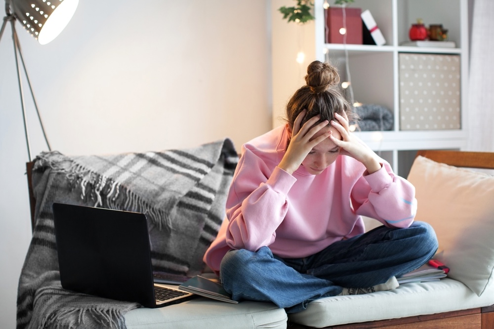 Woman in pink shirt sitting on the couch stressed with studying