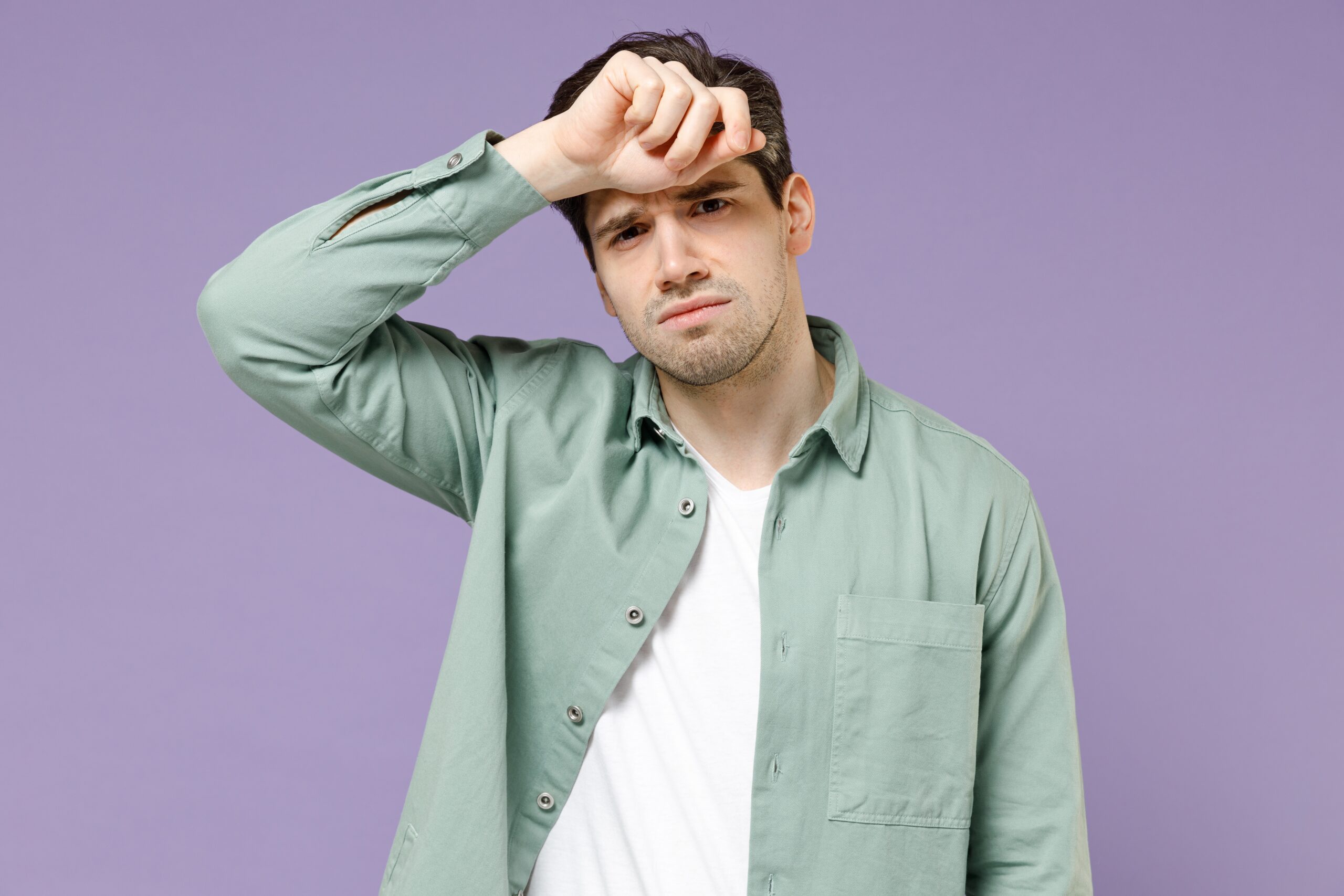 Man wipes his forehead with his forearm while greening out