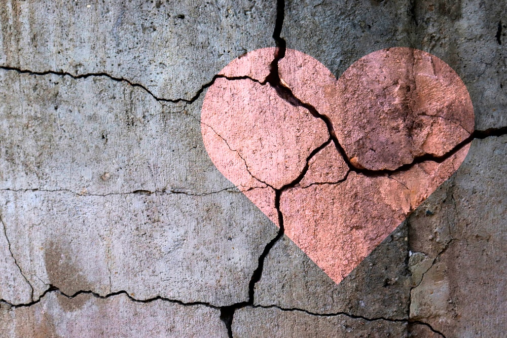 Cracked concrete wall with a painted heart on it
