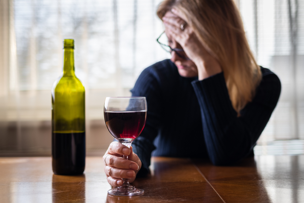 Blonde woman drinking wine wondering if she can be addicted