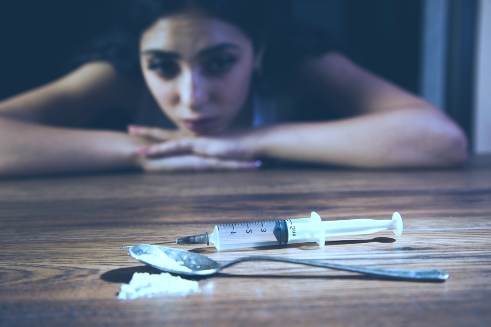Woman who relapsed after rehab looking at drug paraphernalia on a table
