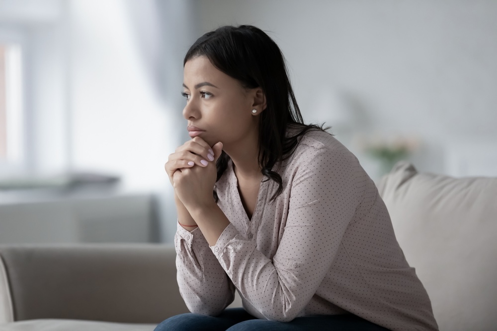 Woman sitting on a couch wondering how to deal with depression in recovery