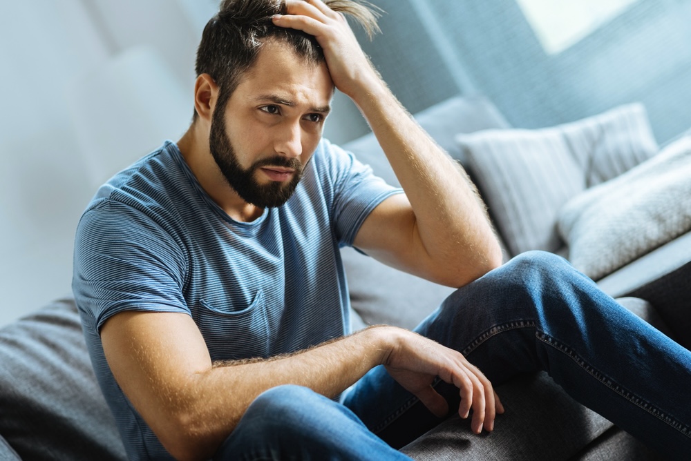 Man holding on to his hair battling depression in addiction recovery