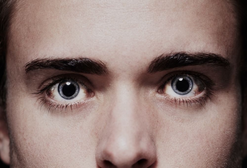 Dilated pupils of a blue-eyed young man using cocaine
