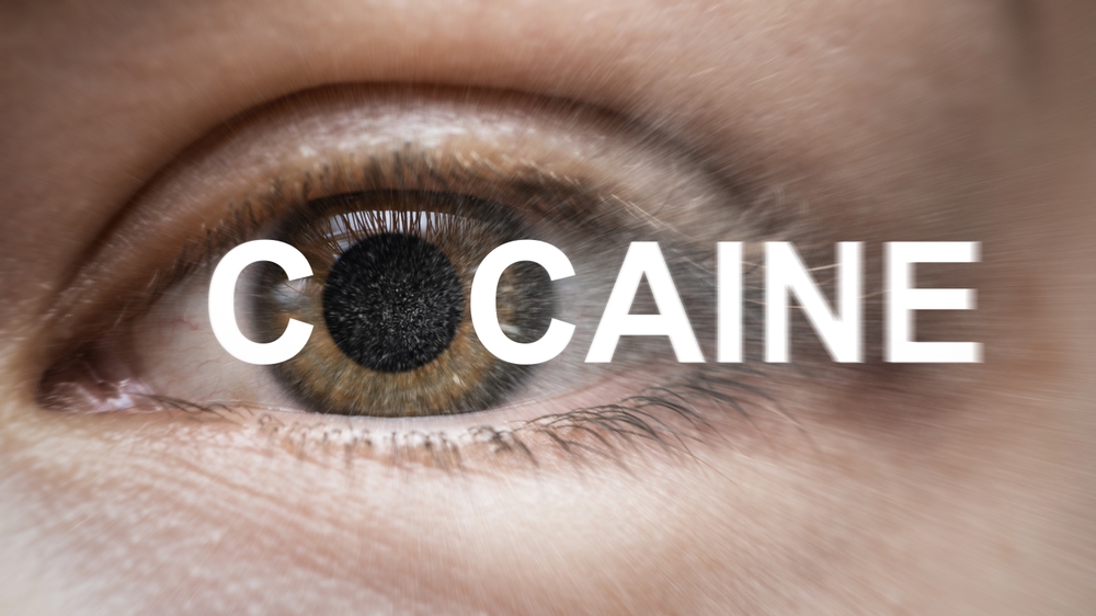 Closeup of eyes with dilated pupils and cocaine written over it