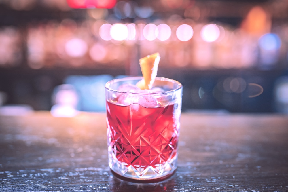 Pink whitney on a cocktail glass on a dimly lit bar
