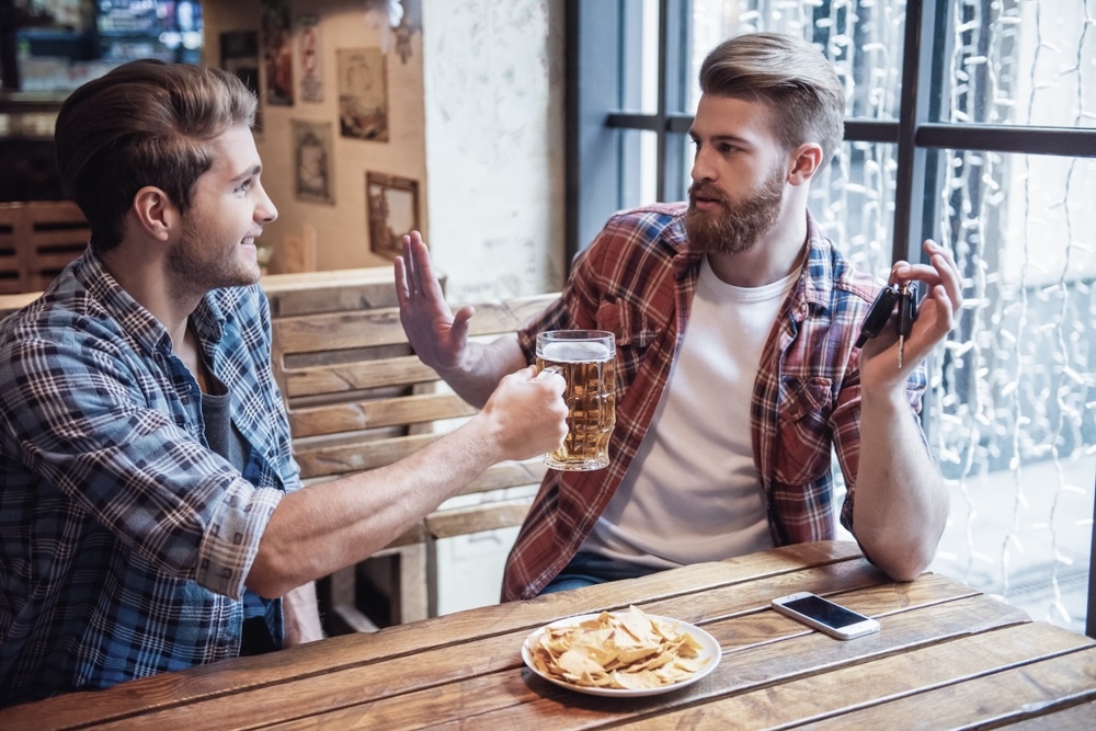 A man saying no to a friend offering alcohol is an external addiction trigger