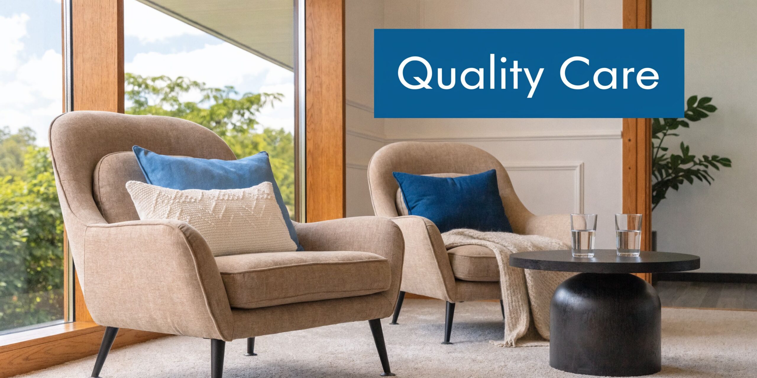 Two comfortable beige armchairs with blue and white cushions arranged in a bright, modern clinic lounge area.