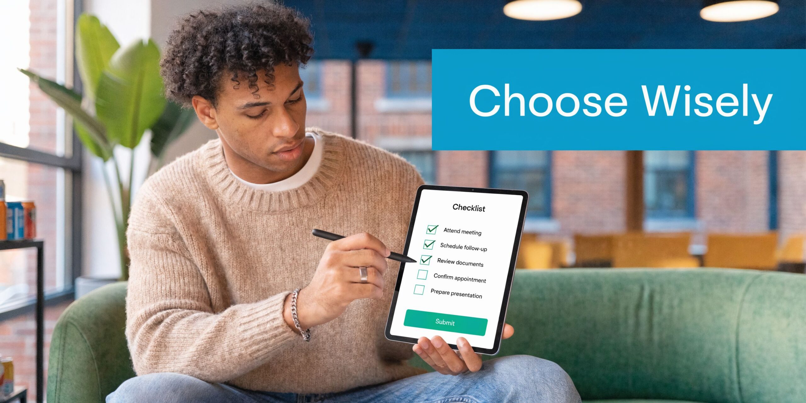 A young man sitting on a sofa and checking off a digital to-do list on his tablet.