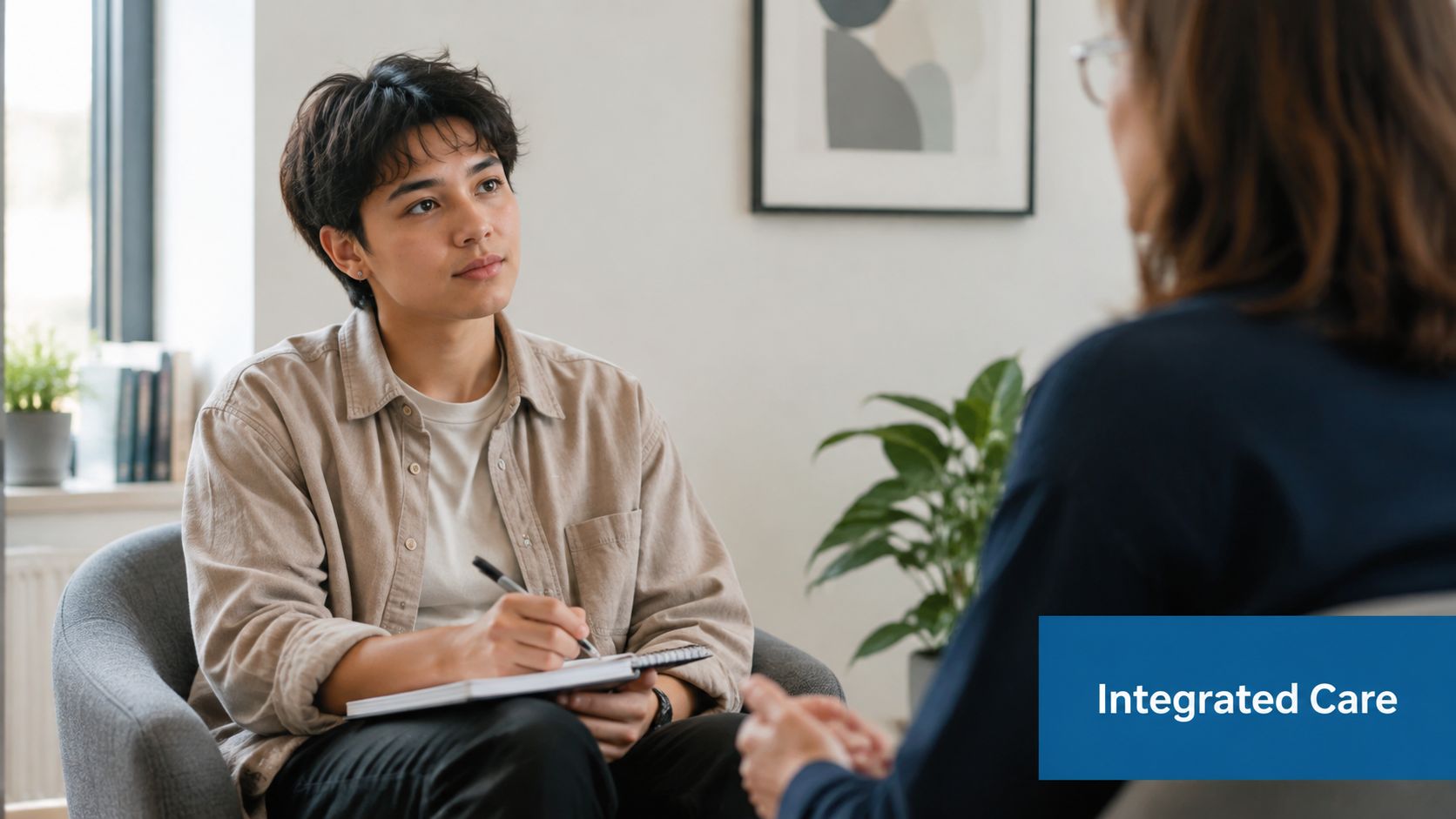 A young person taking notes during a therapy session with a counselor in a clinical setting.